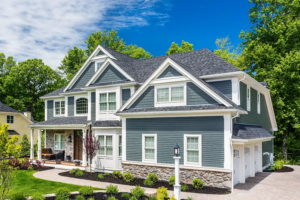 large two-storey home with grey siding, white trim, and a stone foundation — Virginia exterior renovation