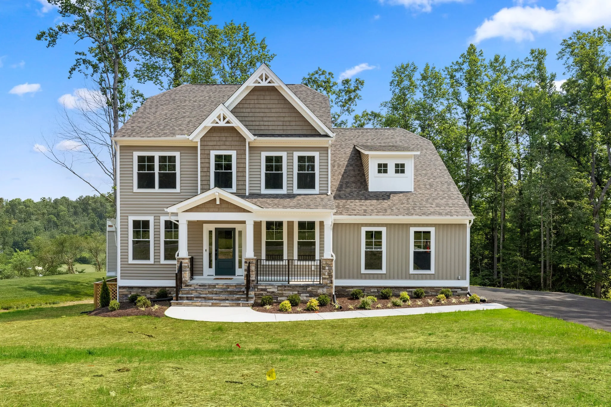 two-storey home with tan vinyl siding, white trim, and a covered front porch