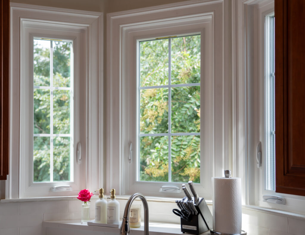 white casement windows overlooking a garden from a bright kitchen interior